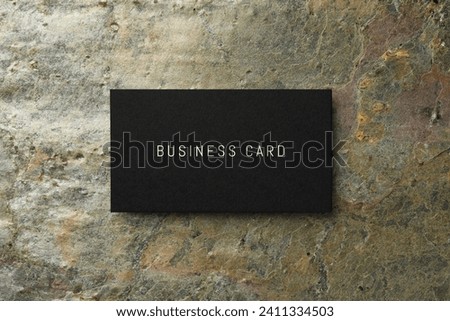 Black business card on color stone background, top view