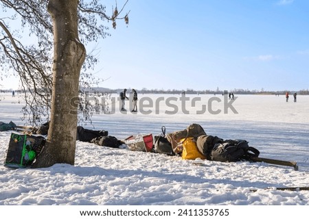 Backpacks and plastic bags of skaters along the frozen lake.