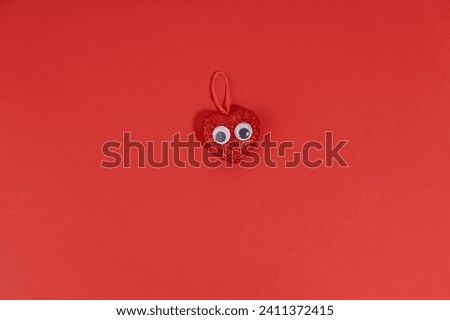 Sparkling red heart with funny eyes St Valentine flat lay concept on red background with copy space