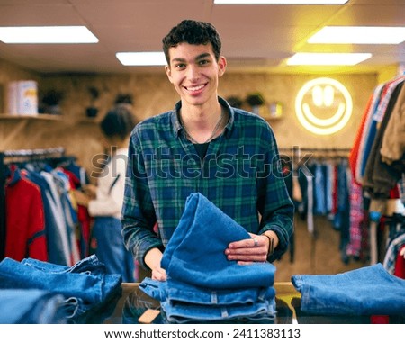 Portrait Of Male Sales Assistant Or Customer Sorting And Looking At Jeans In Fashion Store Royalty-Free Stock Photo #2411383113