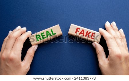 Real or Fake symbol. Concept word Real or Fake on wooden blocks. Businessman hand. Beautiful deep blue background. Business and Real or Fake concept. Copy space Royalty-Free Stock Photo #2411383773
