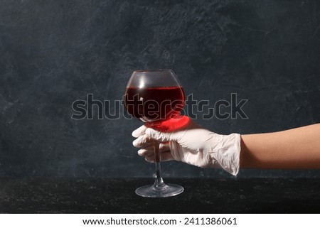 Woman in rubber glove with glass of red wine on dark background