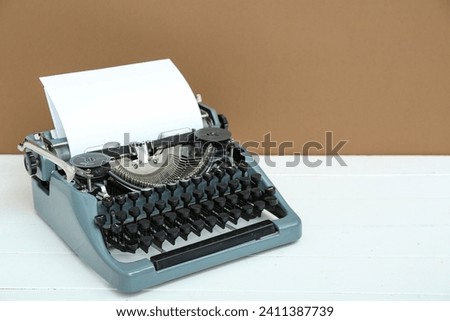 Vintage typewriter on white wooden table near brown wall