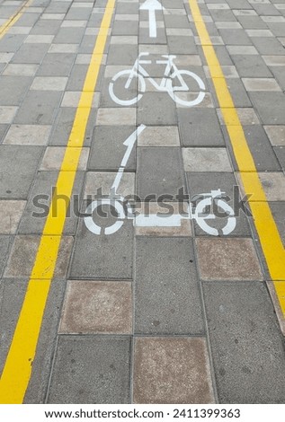 White bicycle and electric bike lane signs or symbols on the pavement. City cycleways and bikeway yellow lines safe tracks or paths for cycle transportation. Sustainable and eco-friendly transport.