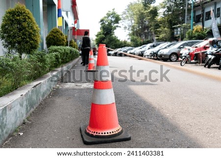 orange traffic cone with rope attached. standing in a row on the road