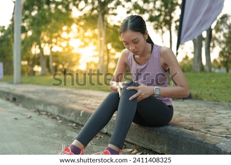 Confident young Asian woman running outdoors along village street. Sitting on the sidewalk resting due to knee pain, sprained knee, sports concepts, health, accidents, health insurance.
