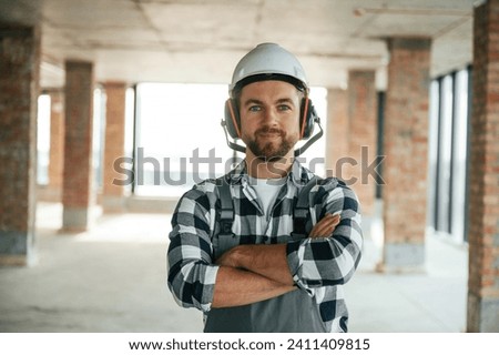 Portrait, in hard hat. Construction worker in uniform in empty unfinished room. Royalty-Free Stock Photo #2411409815