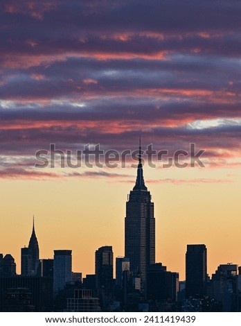 Purple and orange highlighted clouds above midtown Manhattan New York City at sunrise Royalty-Free Stock Photo #2411419439
