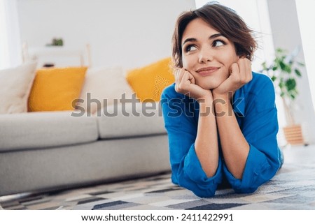 Photo of dreamy adorable cute girl lying on carpet in cozy living room enjoying harmony indoors