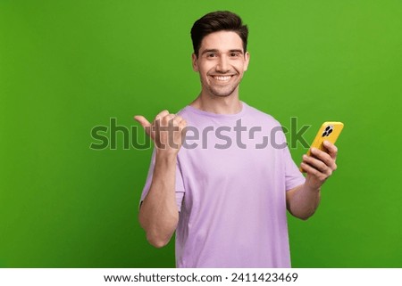 Photo portrait of nice young male point empty space hold gadget dressed stylish purple garment isolated on green color background