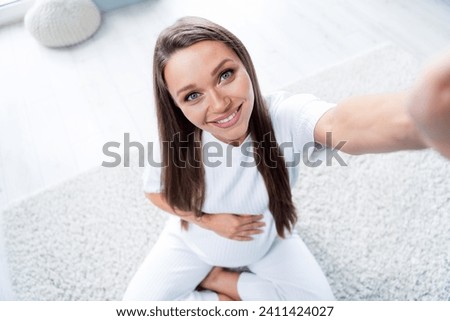 Photo of cute lovely adorable cheerful pregnant girl touching belly making selfie recording video blog indoors