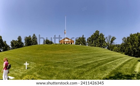 Visitor of Arlington National Cemetery on a grassy lawn with a grave, this is a military cemetery in Washington DC, the capital of the USA. Royalty-Free Stock Photo #2411426345