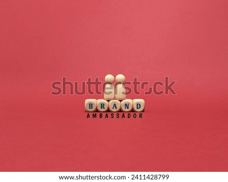 Front view two wooden figure of people on wooden cube with text BRAND AMBASSADOR on red background.