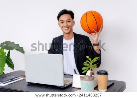 A college student or young employee at his desk holding a basketball. A sports fan or varsity player. White background.