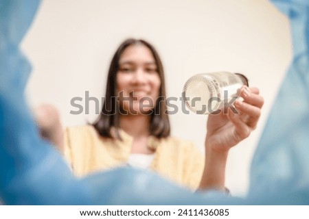 POV selective focus on used glass water bottle dumping in to trash bin by housekeeper. Garbage recycle, glass reuse house waste sorting for sustainable life concept. Royalty-Free Stock Photo #2411436085