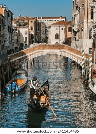 Venetian gondolier rowing on the canal in black and white striped sweater Royalty-Free Stock Photo #2411454485
