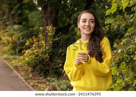Beautiful young woman in stylish warm sweater outdoors, space for text