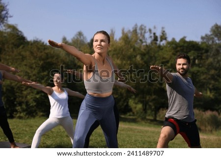 Group of people practicing yoga in park on sunny day, selective focus