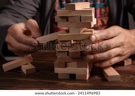 Hand of engineer playing a blocks wood tower game on blueprint or architectural project. Royalty-Free Stock Photo #2411496983