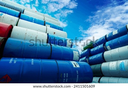 Stack of old chemical barrels. Blue, green, and red oil drum. Steel oil tank. Toxic waste warehouse. Hazard chemical barrel with red flammable liquid warning label. Hazard waste storage in a factory. Royalty-Free Stock Photo #2411501609