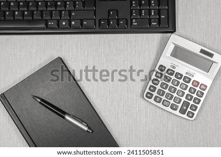Closed book without inscription with a calculator on a work surface. For background creation.	