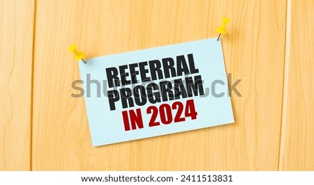 REFERRAL PROGRAM 2024 sign written on sticky note pinned on wooden wall