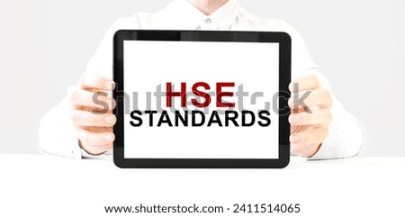 Text HSE STANDARDS on tablet display in businessman hands on the white background. Business concept