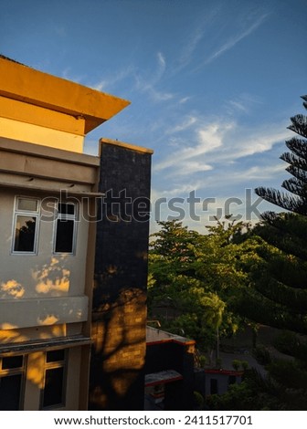 The campus buildings are accompanied by blue skies and shady green trees at dusk  Royalty-Free Stock Photo #2411517701