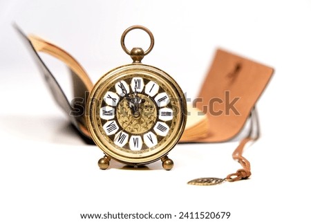 an old golden analog alarm clock with mechanical movement isolated on a white background with notebook