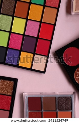 Various colorful eyeshadow palettes on bright pink background. Flat lay.