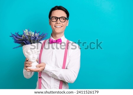 Photo portrait of handsome young guy look empty space hold head vase dressed stylish pink garment isolated on aquamarine color background