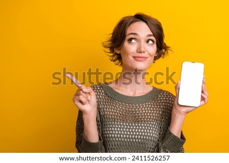 Photo of pretty young girl white display point look empty space dressed stylish knitted khaki outfit isolated on yellow color background