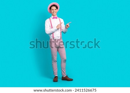 Full body photo of positive guy wear white shirt pink headwear indicating at discount empty space isolated on blue color background