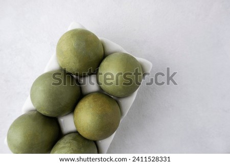 Green eggs in a white tray on a light background. Minimal concept. View from above. Easter eggs. Photo of preparations for Easter.