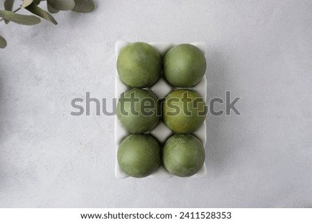 Green eggs in a white tray on a light background. Minimal concept. View from above. Easter eggs. Photo of preparations for Easter.