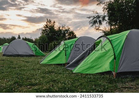 Tourist vibe. Group of tents set up in a field at sunset.