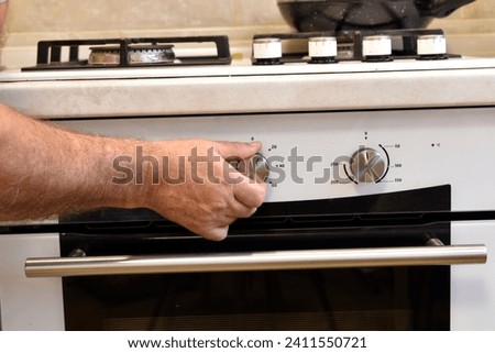 In the picture, the male hand that turns the handle on the oven panel.
