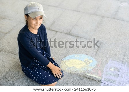 little girl draws on the pavement.