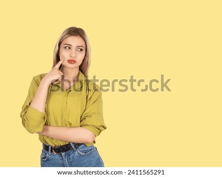 Deep thinking woman, close up photo of beautiful blonde deep thinking woman. Touching her cheek, looking aside. Thoughtful face expression. Light yellow background, copy space.