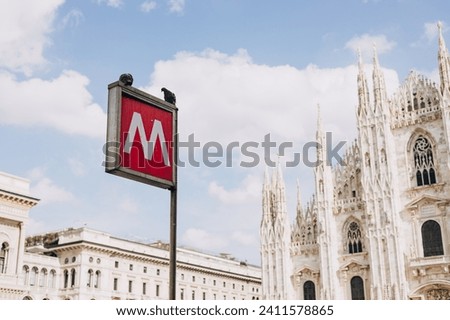 An underground subway metro tube traffic sign in Milan, Italy. sign metro station with blurred Milan Cathedral church