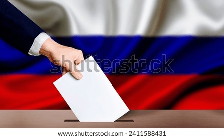 Hand holding ballot in the ballot box with Russia flag in the background. Presidential elections of the Russian Federation Royalty-Free Stock Photo #2411588431