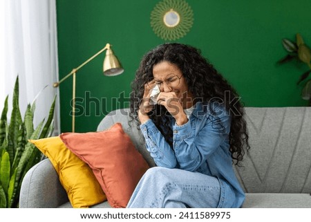 Lonely sad woman crying sitting at home on sofa in living room of house, Hispanic woman in distress and depression hopelessness. Royalty-Free Stock Photo #2411589975