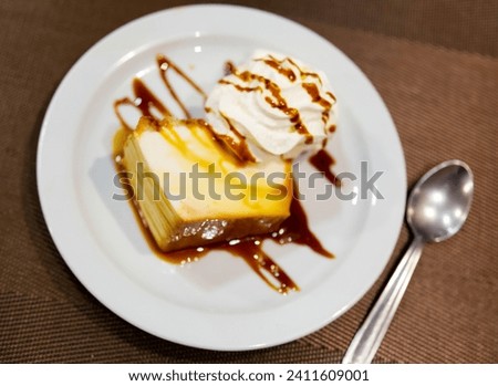 In center of picture is baked custard flan, complemented with whipped cream. Delicate dessert to treat guests