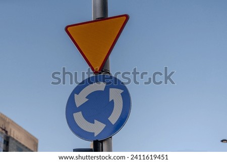 Yield and roundabout road signs mounted on a pole in Warsaw