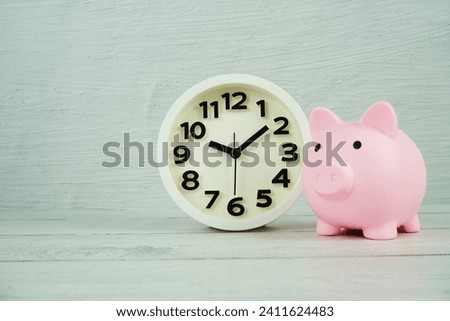 Time to save concept background with piggy bank and clock on wooden background