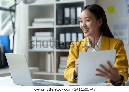 Asian businesswoman, investor, insurance salesperson pointing at data sheet. Earnings. Chart showing financial growth in real estate business based on data from laptop. Modern working lifestyle.