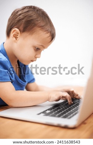 Boy kid, laptop and typing in home, reading or search for movie, cartoon or elearning for development. Child, computer and click keyboard at desk in family house for education, study or online course