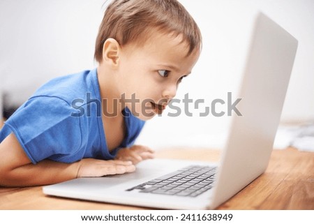 Boy child, laptop and reading in home with search, movies and cartoon with learning video for development. Kid, computer and watch at desk in family house for education, studying and online course