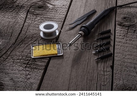 Soldering Iron with Solder, Tweezer and Tips on Wooden Background. File with Clipping Path. Royalty-Free Stock Photo #2411645141