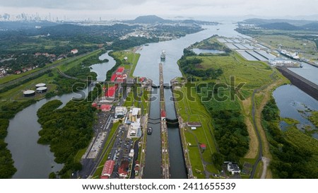 Aerial view Panama Canal, third set of locks, water shortages, maritime traffic, water reuse vats, summer drought. Royalty-Free Stock Photo #2411655539